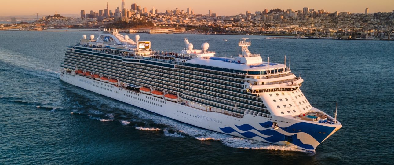 a large cruise ship in the ocean with a city in the background