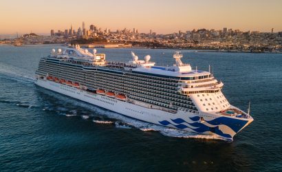 a large cruise ship in the ocean with a city in the background