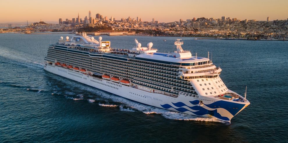 a large cruise ship in the ocean with a city in the background